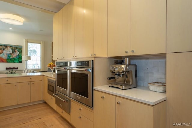 kitchen featuring appliances with stainless steel finishes, kitchen peninsula, light hardwood / wood-style floors, and decorative backsplash