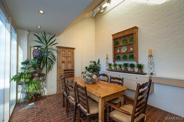 dining room featuring brick wall and a towering ceiling