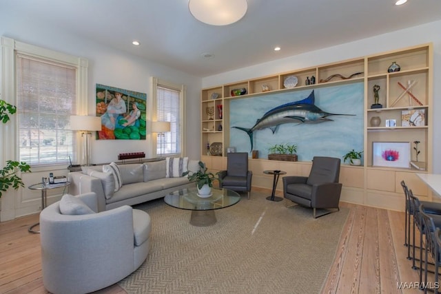 living room with a wealth of natural light, built in features, and light wood-type flooring