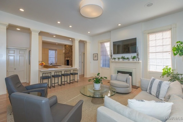 living room featuring decorative columns, sink, and light wood-type flooring