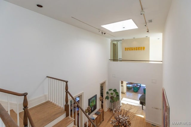 staircase featuring hardwood / wood-style floors, track lighting, and a skylight