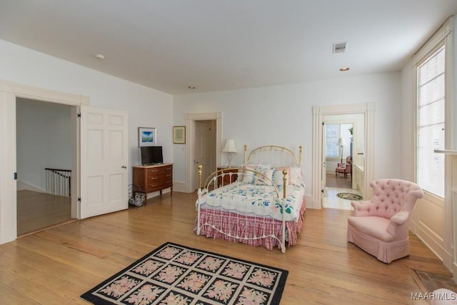 bedroom with multiple windows and light hardwood / wood-style flooring