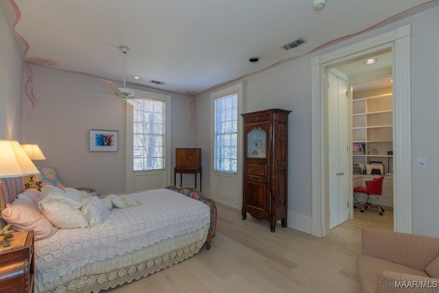 bedroom with a walk in closet, a closet, and light hardwood / wood-style flooring