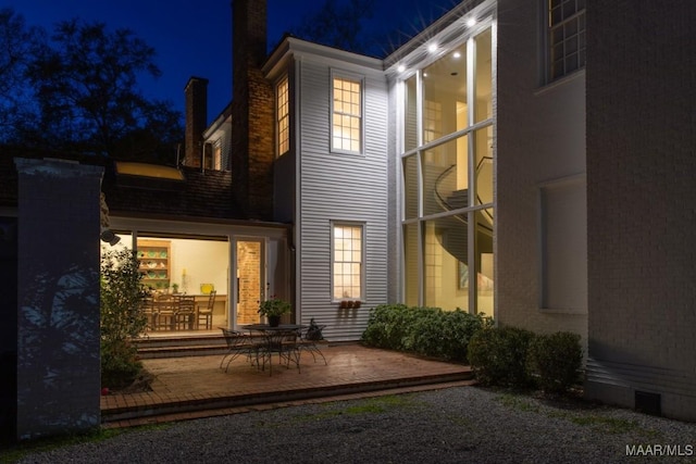 back house at night featuring a patio