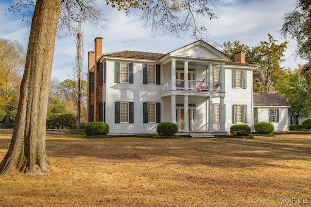 neoclassical / greek revival house with a balcony and a front lawn