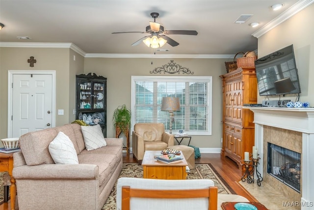 living room featuring ornamental molding, a premium fireplace, ceiling fan, and light wood-type flooring