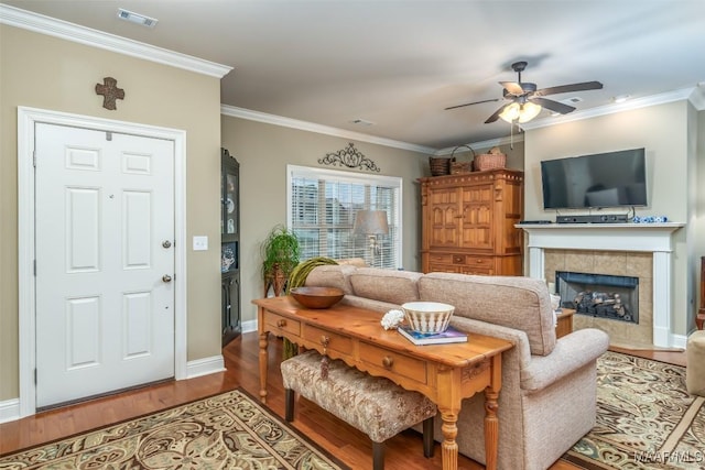 living room featuring hardwood / wood-style flooring, a fireplace, crown molding, and ceiling fan