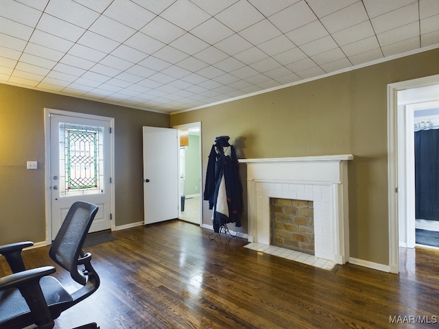 office featuring a tile fireplace, dark wood-type flooring, and crown molding