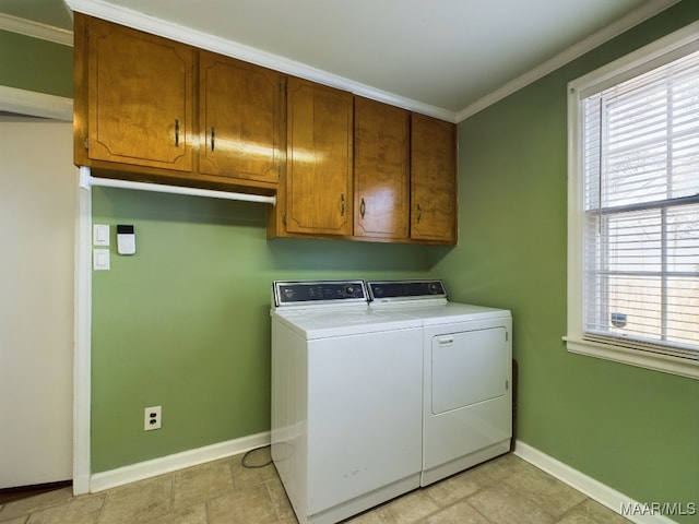 clothes washing area featuring crown molding, cabinets, and washer and clothes dryer