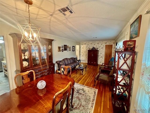 dining space featuring hardwood / wood-style flooring, crown molding, a textured ceiling, and a chandelier