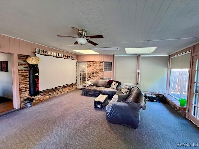 carpeted living room featuring brick wall, ceiling fan, and wood walls