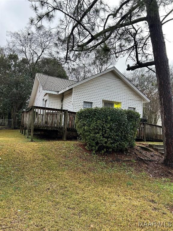 view of side of home with a wooden deck and a yard