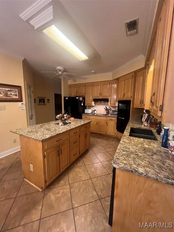 kitchen featuring sink, light stone counters, ornamental molding, black appliances, and a kitchen island