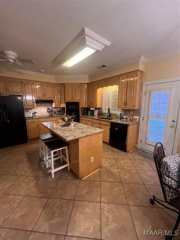 kitchen featuring a kitchen island, a kitchen bar, tile patterned flooring, ornamental molding, and black appliances