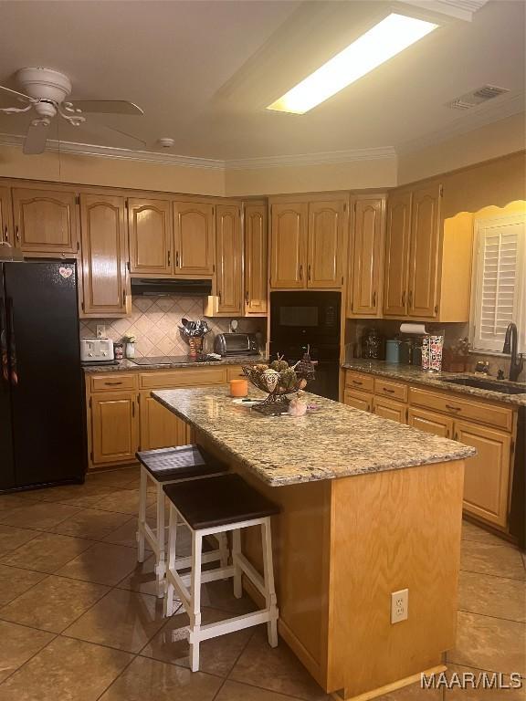 kitchen with a breakfast bar, sink, a kitchen island, and black appliances