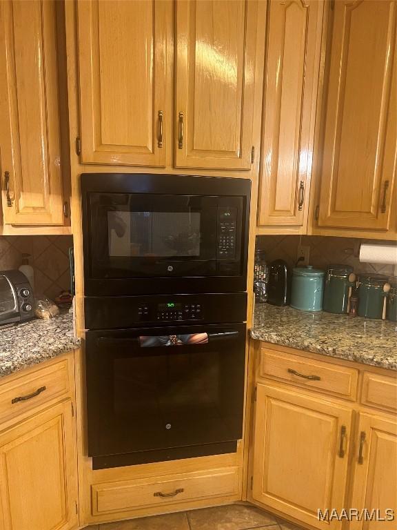 kitchen with tasteful backsplash, light stone countertops, and black appliances