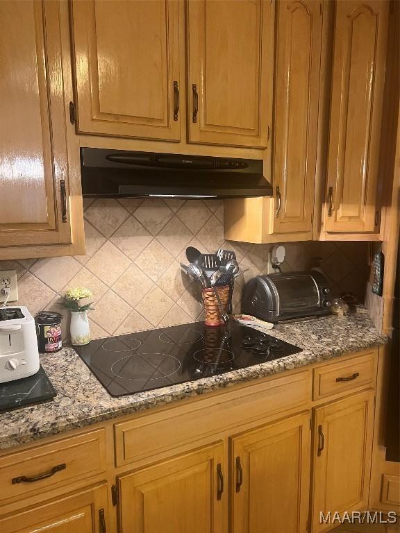 kitchen with black electric cooktop, backsplash, and stone countertops