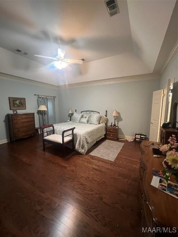 bedroom featuring hardwood / wood-style flooring, ceiling fan, ornamental molding, and a raised ceiling