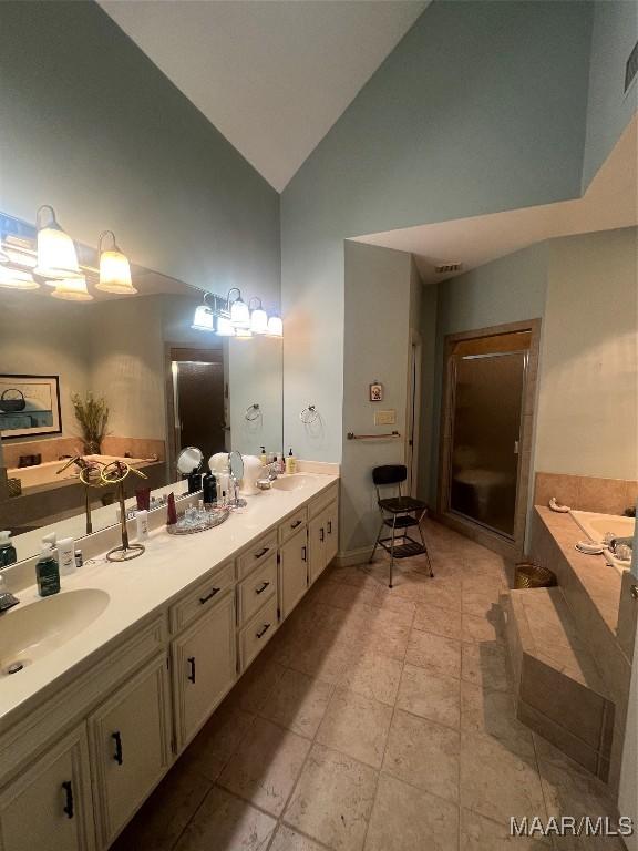 bathroom featuring vanity, tile patterned flooring, high vaulted ceiling, and tiled bath