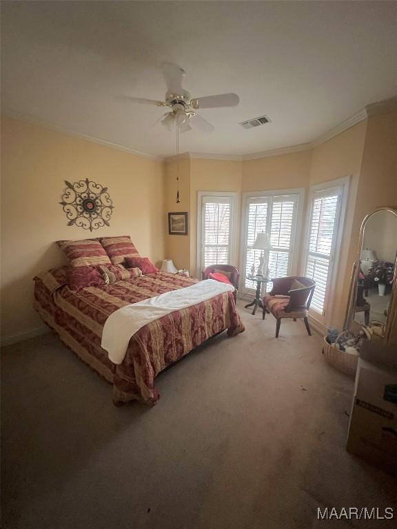 carpeted bedroom with multiple windows, ornamental molding, and ceiling fan