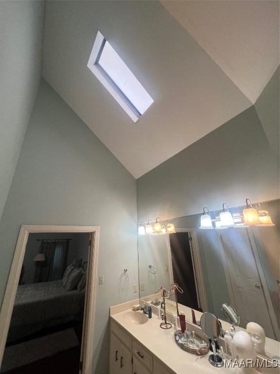 bathroom featuring vanity, a skylight, and high vaulted ceiling