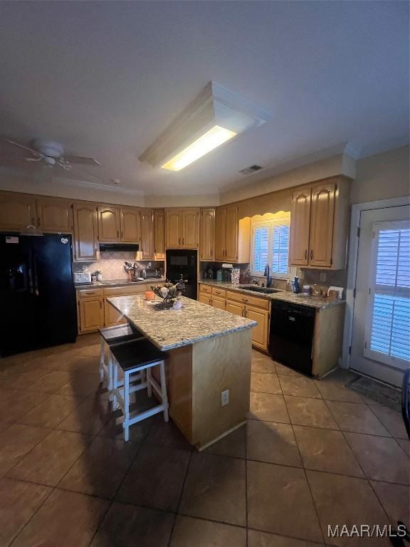 kitchen with sink, a center island, a kitchen breakfast bar, decorative backsplash, and black appliances