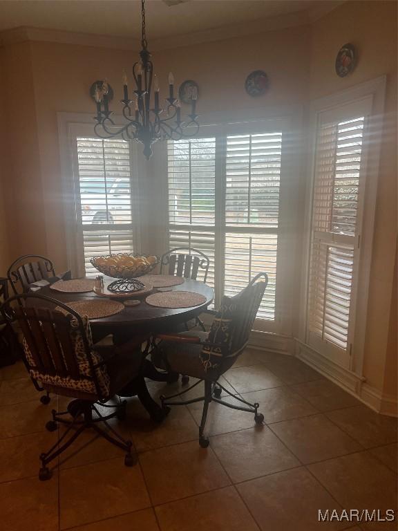 tiled dining area with crown molding and an inviting chandelier