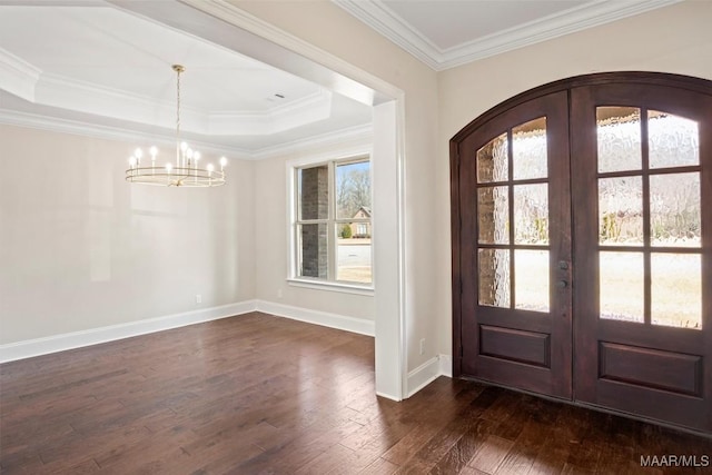 entryway with dark hardwood / wood-style flooring, ornamental molding, a raised ceiling, an inviting chandelier, and french doors