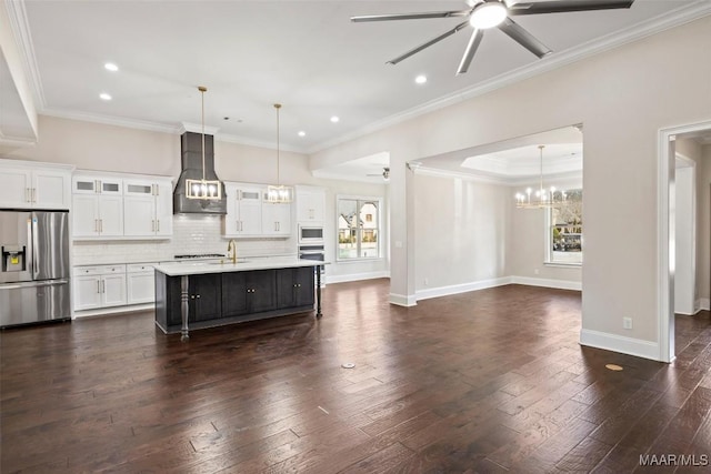 kitchen featuring appliances with stainless steel finishes, pendant lighting, white cabinets, custom range hood, and a center island with sink