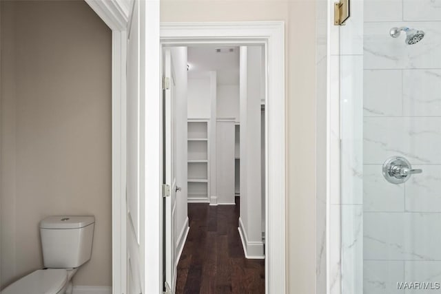 bathroom featuring a tile shower, hardwood / wood-style floors, and toilet