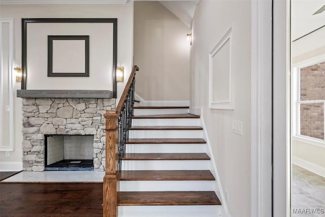 staircase with a fireplace and wood-type flooring