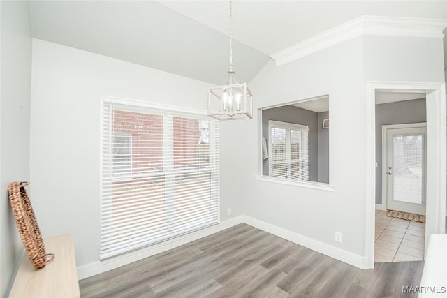 unfurnished dining area with crown molding, light hardwood / wood-style floors, vaulted ceiling, and a notable chandelier