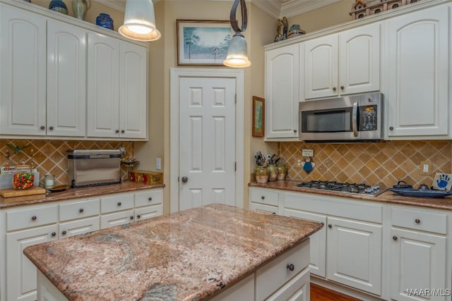 kitchen with pendant lighting, white cabinetry, light stone countertops, and appliances with stainless steel finishes