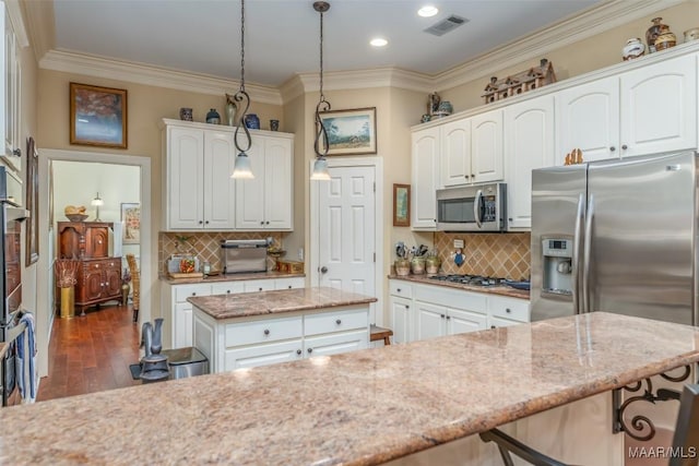 kitchen with stainless steel appliances, decorative light fixtures, a center island, and white cabinets