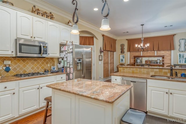 kitchen featuring sink, a breakfast bar, appliances with stainless steel finishes, hanging light fixtures, and white cabinets