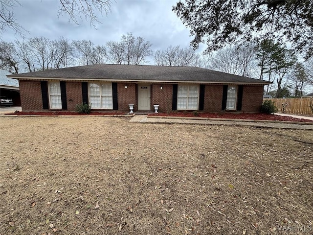 ranch-style home with brick siding, fence, and roof with shingles
