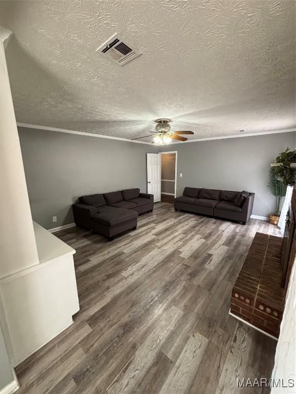 living room featuring a textured ceiling, visible vents, wood finished floors, and a ceiling fan