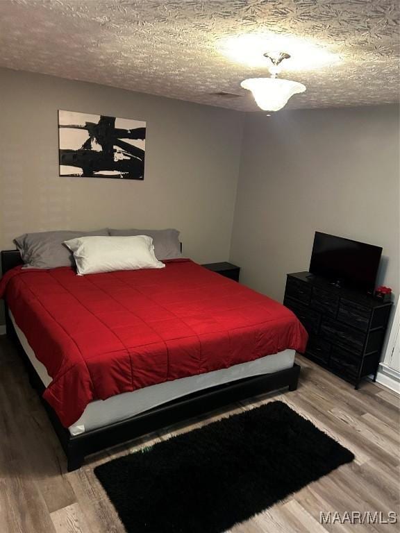 bedroom with a textured ceiling and light wood finished floors