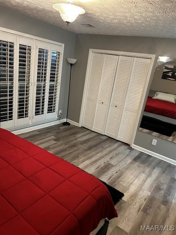 bedroom with baseboards, a closet, wood finished floors, and a textured ceiling