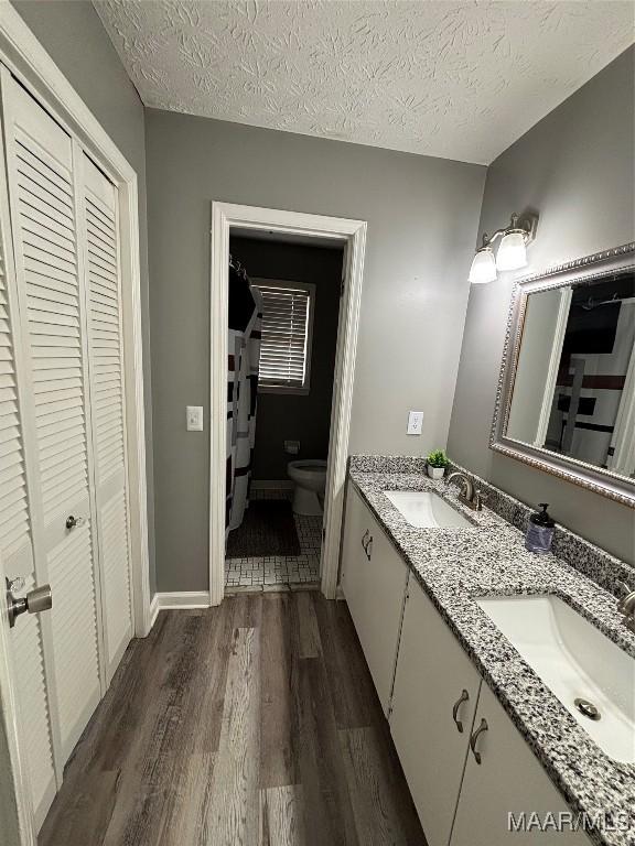 bathroom featuring vanity, toilet, hardwood / wood-style floors, and a textured ceiling