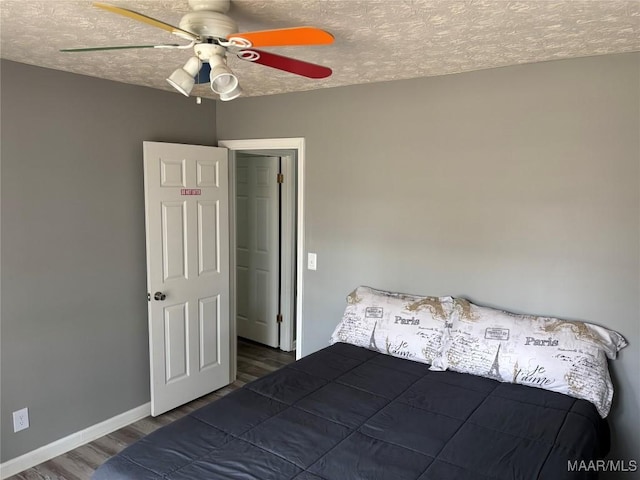 unfurnished bedroom featuring baseboards, a textured ceiling, wood finished floors, and ceiling fan