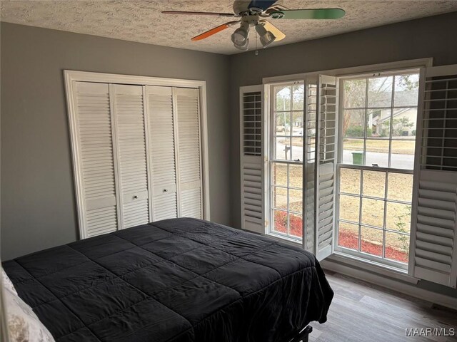 bedroom with hardwood / wood-style flooring, a closet, ceiling fan, and a textured ceiling