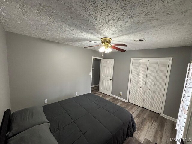 bedroom with hardwood / wood-style flooring, a textured ceiling, ceiling fan, and a closet