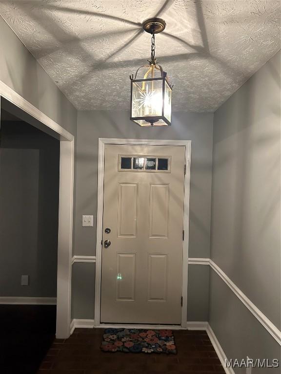 foyer featuring baseboards, dark wood-type flooring, and a textured ceiling