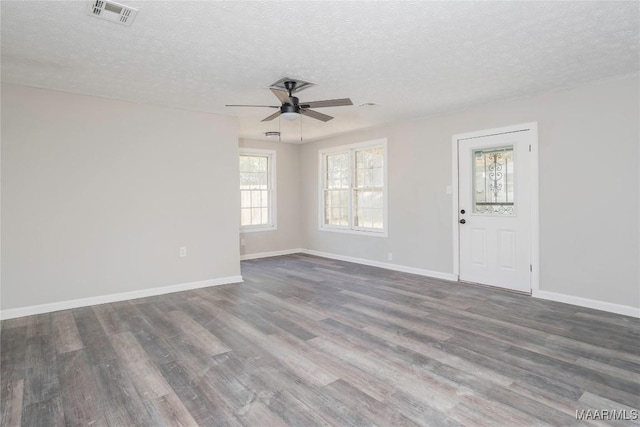 empty room featuring ceiling fan, dark wood-type flooring, and a textured ceiling