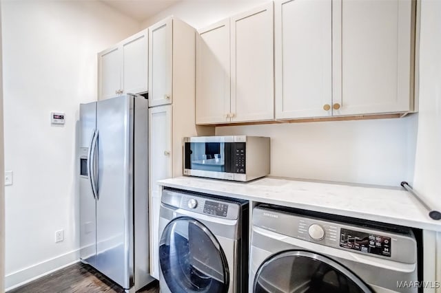 clothes washing area with dark wood-style floors, washer and dryer, and baseboards