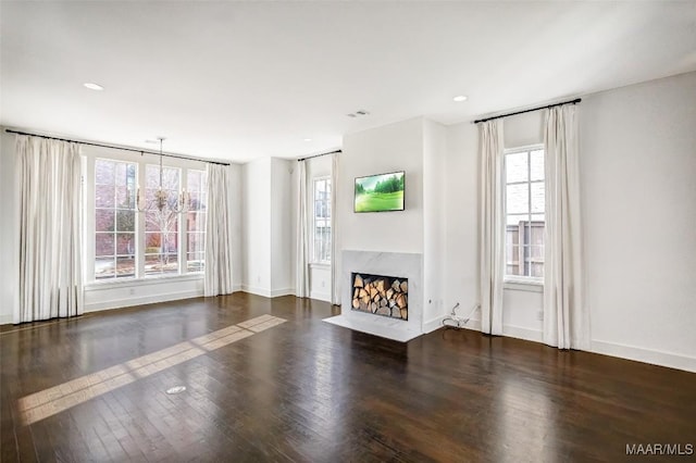 unfurnished living room with visible vents, baseboards, dark wood finished floors, a premium fireplace, and recessed lighting