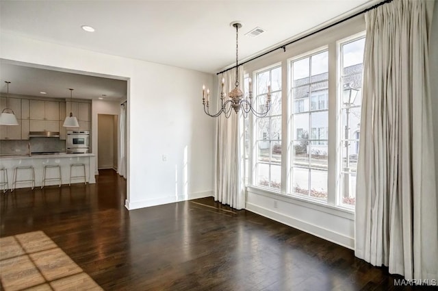 unfurnished dining area with dark wood-style floors, a wealth of natural light, visible vents, and baseboards