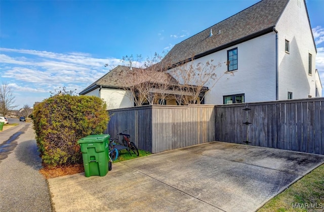 view of side of home featuring brick siding, a patio area, and fence