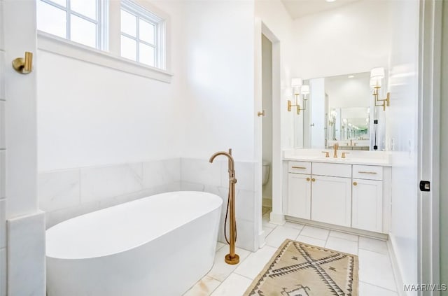 full bath with toilet, tile walls, vanity, a soaking tub, and tile patterned floors